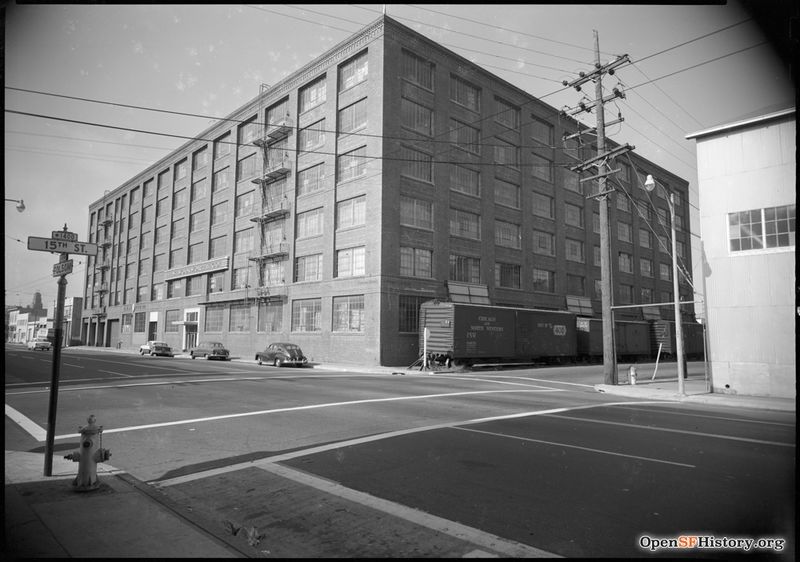 File:C 1955 View toward Northeast Corner of 15th and Folsom. Woolworth Company warehouse with railroad boxcars on 15th, presently occupied by the University of California San Francisco Mission Center. wnp100.00107.jpg