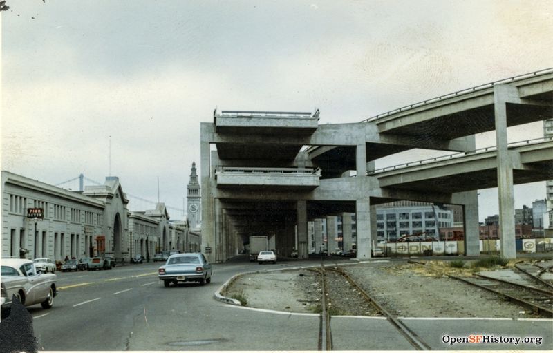 File:C1965 Embarcadero Freeway end, with off ramp curving to Broadway. Ferry Building in distance. Pier Seven Cocktails sign, belt line rails wnp27.6035.jpg