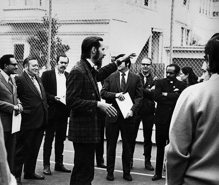 File:Plaid-jacketed-guy-w-goatee-addressing-MCO-and-dignitaries-in-schoolyard.jpg